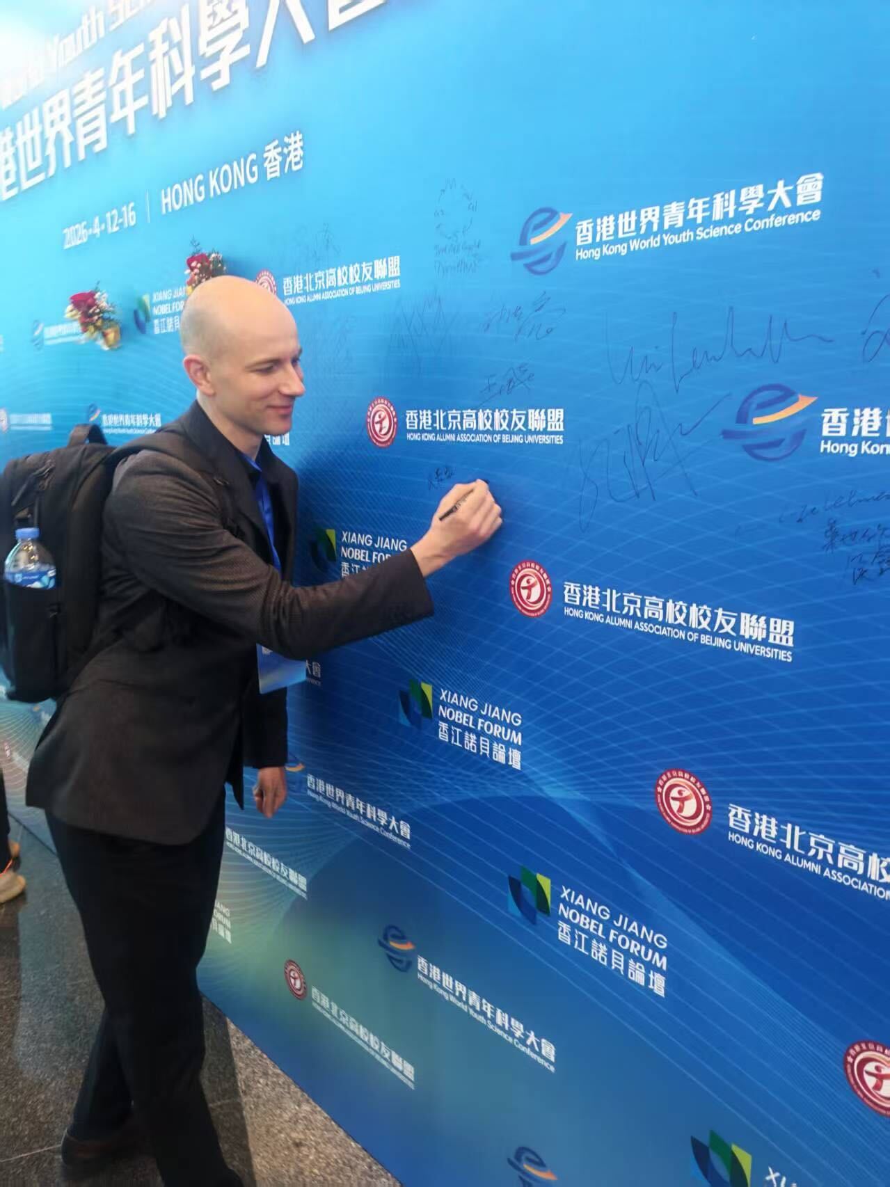 A speaker signs the HKWYSC 2026 conference wall